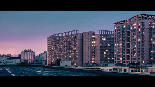 Modern buildings against sky in city at dusk