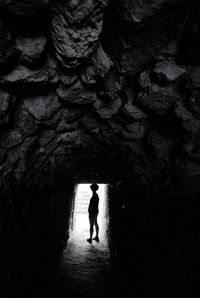 Rear view of woman standing in cave