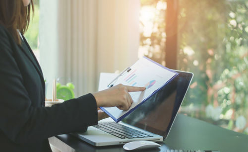 Midsection of woman using laptop on table