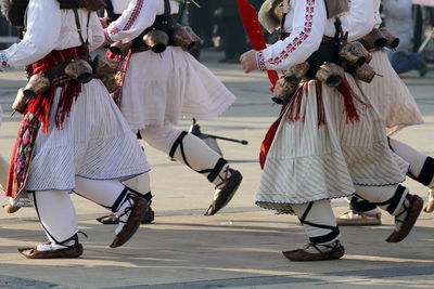 Low section of men in traditional clothing dancing on road