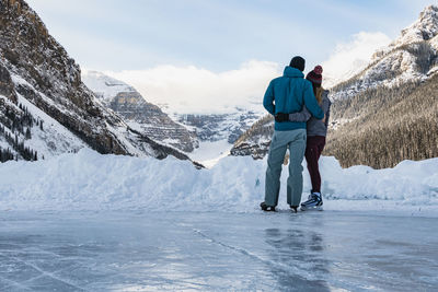 Young couple ice skating on lake louise enjoy scenic mountain view