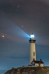 Illuminated lighthouse against sky at night