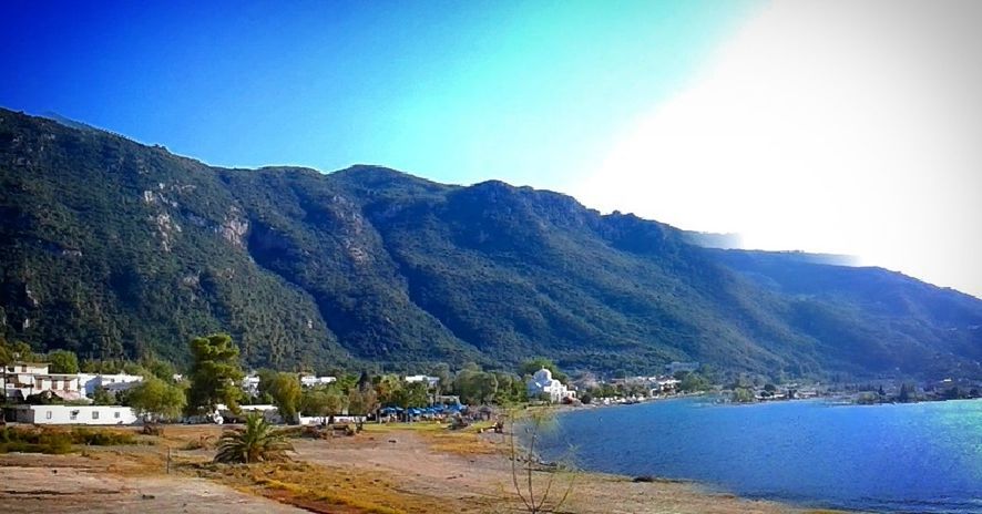 mountain, water, mountain range, blue, scenics, tranquility, tranquil scene, beauty in nature, nature, day, landscape, outdoors, sky, idyllic, hill, town, no people, non-urban scene, coastline, remote, travel destinations