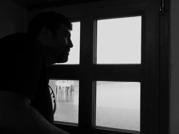 Man looking through window at lake