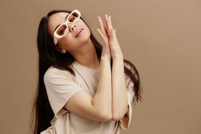 Close-up of young woman wearing sunglasses against pink background