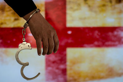 Cropped hand of male criminal with handcuffs against british flag