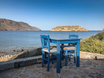 Chairs and tables on beach against clear blue sky