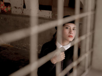 Portrait of young woman looking away while standing by railing