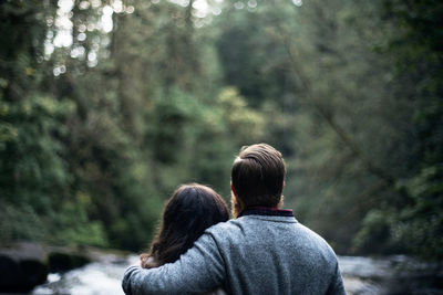 Rear view of couple sitting in forest