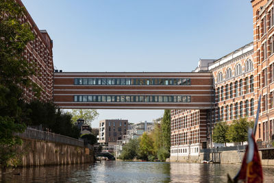 Buildings by river against clear sky