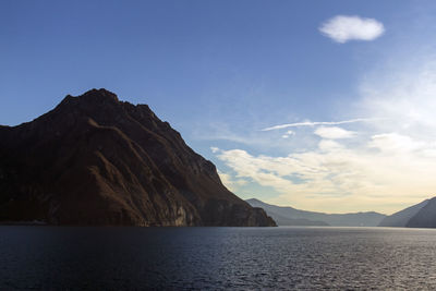 Scenic view of sea by mountains against sky