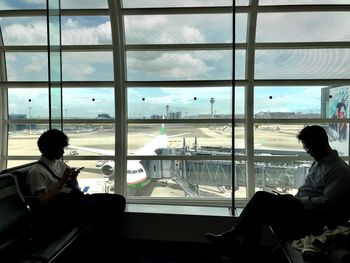 Rear view of man looking through airplane window