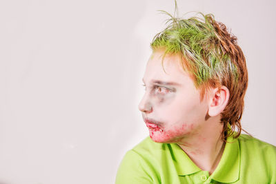 Close-up of teenage boy in zombie make-up against wall