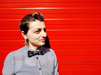 Woman standing against red wall