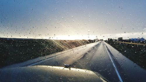 Waterdrops on glass with view of road seen through car window