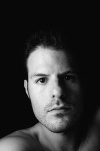 Portrait of young man against black background