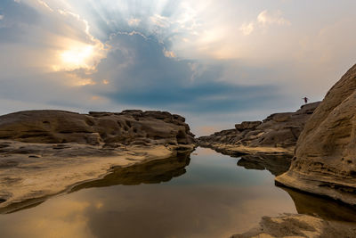 Rock formations by sea against sky during sunset