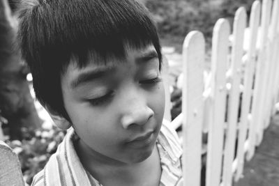 Close-up of boy with eyes closed standing by fence