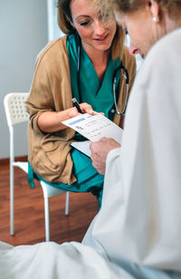 Nurse showing prescription paper to senior patient in hospital