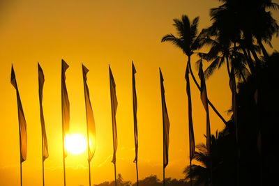 Low angle view of silhouette palm trees against orange sky