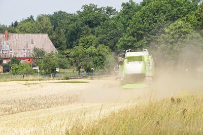 Agricultural machinery on field against trees