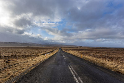 Road amidst field against sky