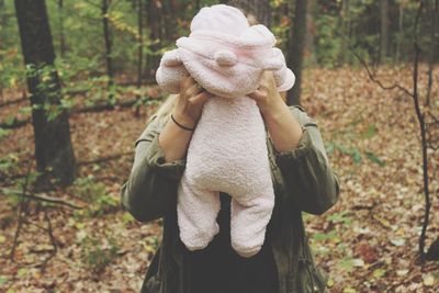 Mother holding baby amidst trees at forest