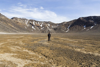 Rear view of man standing on mountain against sky