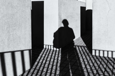 Rear view of man walking on footpath against building