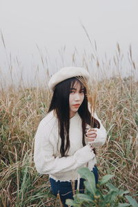 Young woman holding hat on field