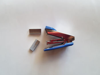 High angle view of stapler and pins over white background