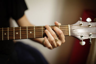 Cropped image of woman playing guitar at home