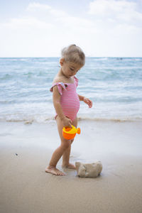 Cute toddler girl playing with water on the beach. vacation on the sea shore concept. summertime fun