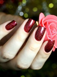 Cropped image of woman hand with red nail polish holding artificial rose