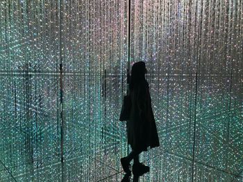 Rear view of woman standing on wet glass
