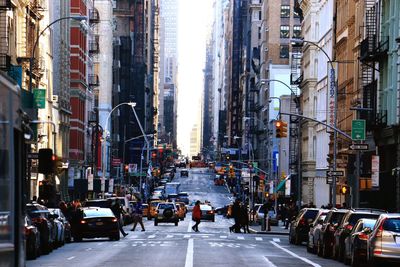 People and cars on street amidst buildings in city