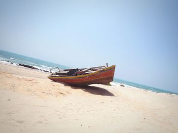 Lounge chairs on beach against clear sky