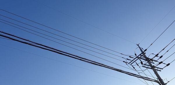 Low angle view of power lines against clear blue sky