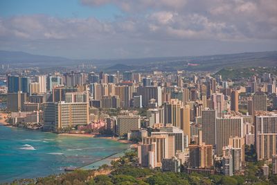 Aerial view of city by sea against sky