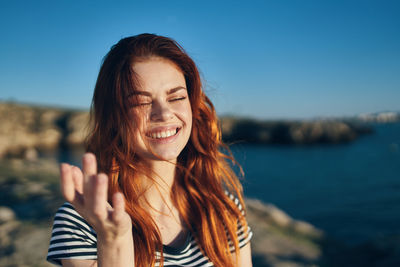 Portrait of smiling young woman against sky