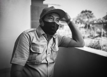 Portrait of young man wearing hat standing against wall