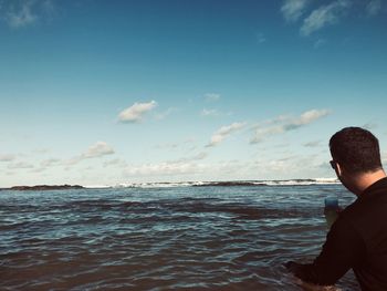 Rear view of man on beach against sky