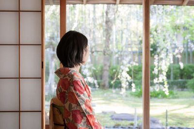 Rear view of woman standing against window