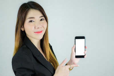Portrait of a smiling young woman using smart phone against white background