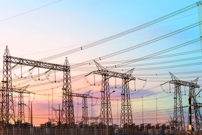 Low angle view of silhouette electricity pylon against sky during sunset