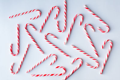 Overhead image of candy canes scattered on a plain white background.