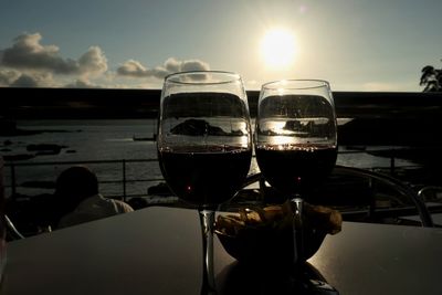 Wine glass on table against sky during sunset