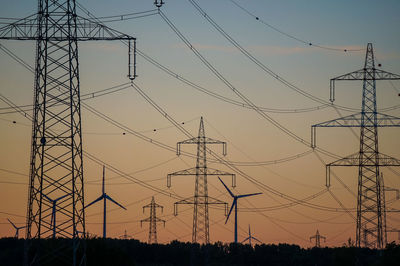 Low angle view of silhouette electricity pylon against sky during sunset