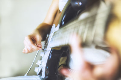 Midsection of person playing guitar at home