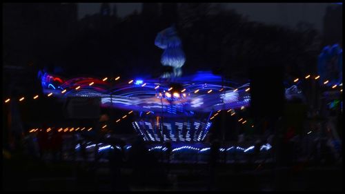 Illuminated ferris wheel in city at night